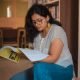 A woman reading a book in a library, creating a focused and serene atmosphere.